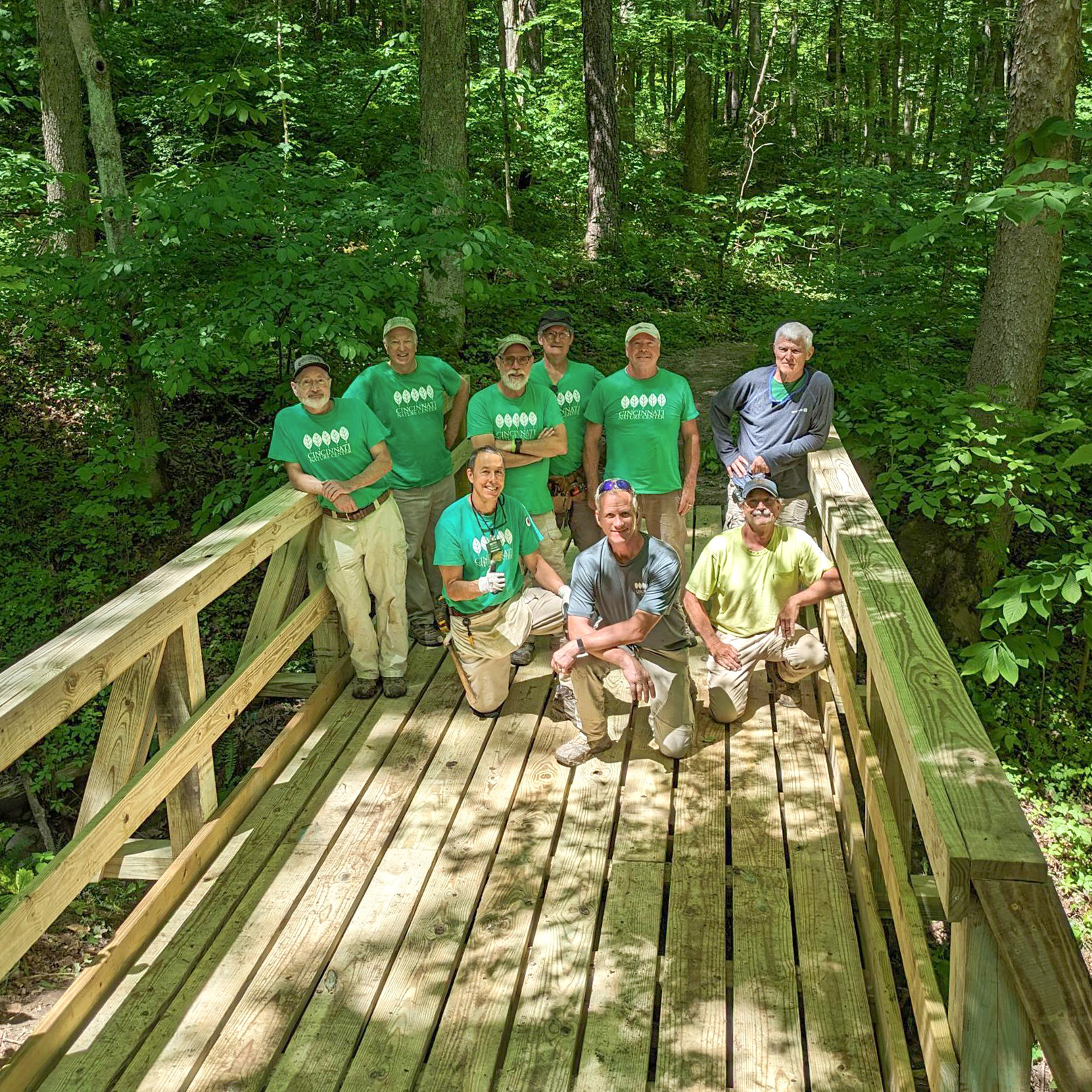 Volunteers and Troy pose for a group photo on the newly constructed bridge.